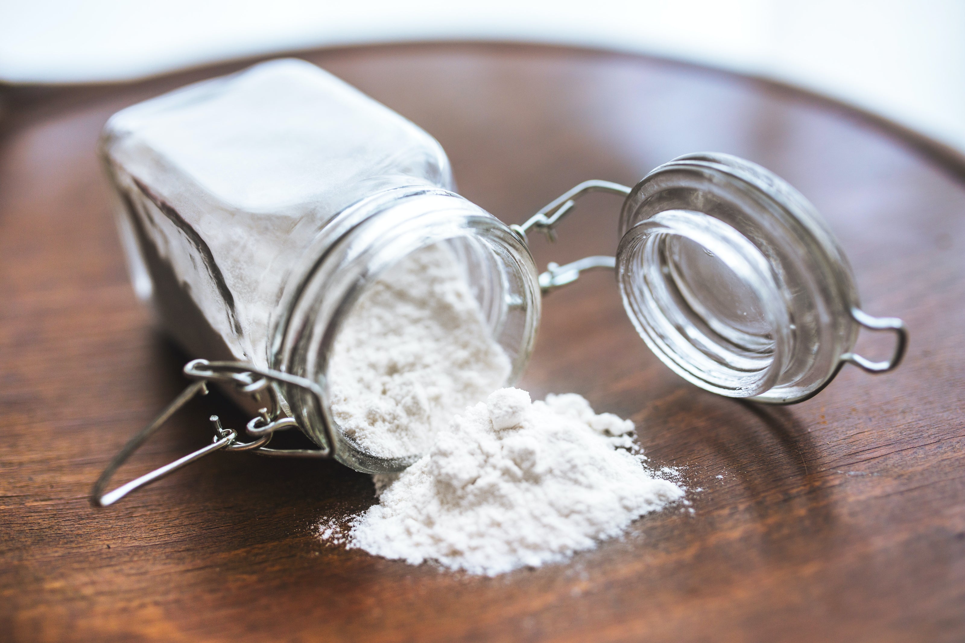 A bottle of baking soda tipped over and spilled out onto a wooden table